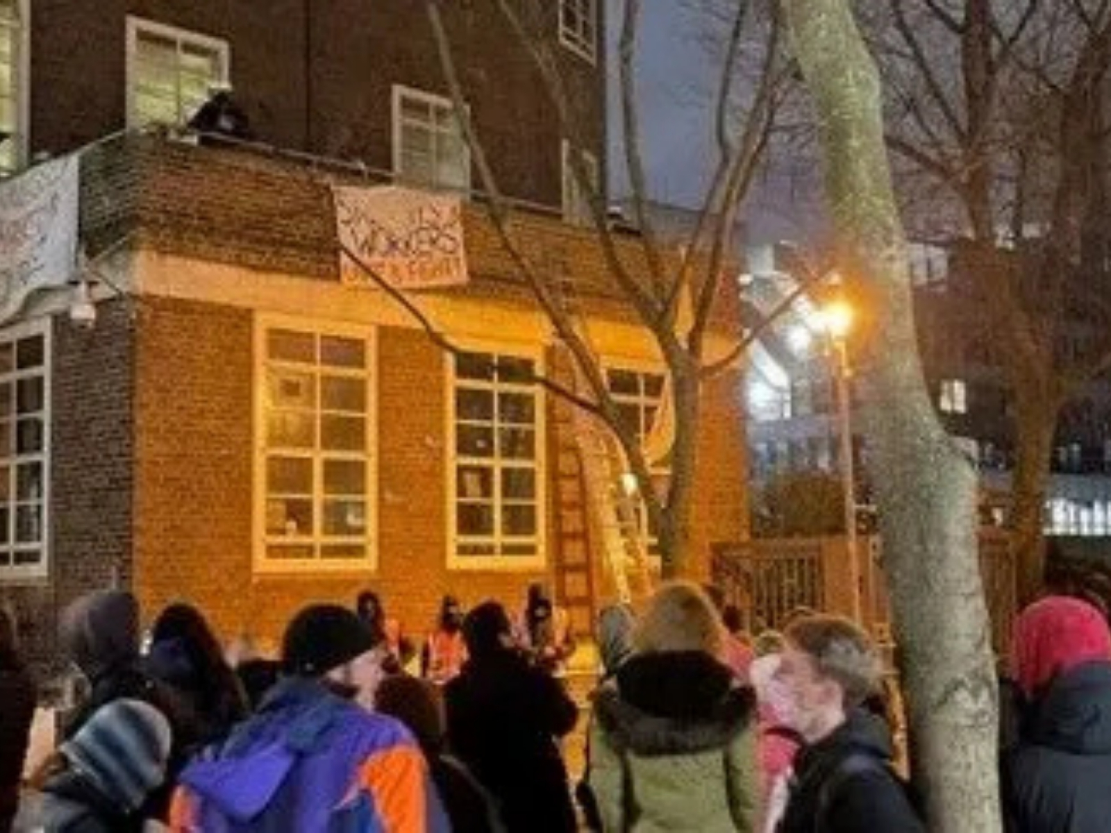 Crowd outside a lit SOAS building at night during the eviction